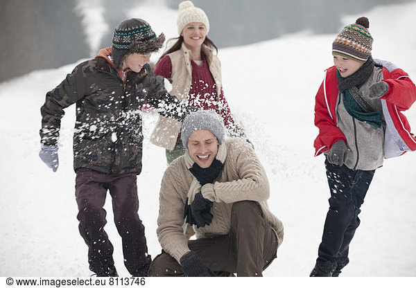 Playful family enjoying snowball fight in field