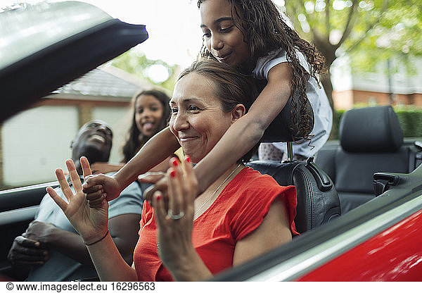 Playful family riding in convertible