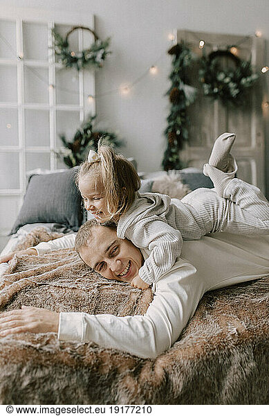 Playful father and daughter lying on bed at home