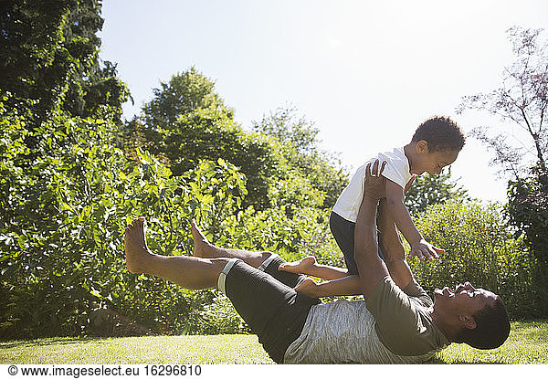 Playful father and son in sunny summer backyard