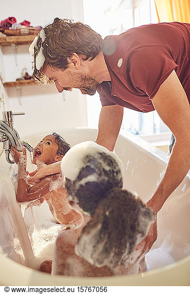 Playful father giving daughters bubble bath