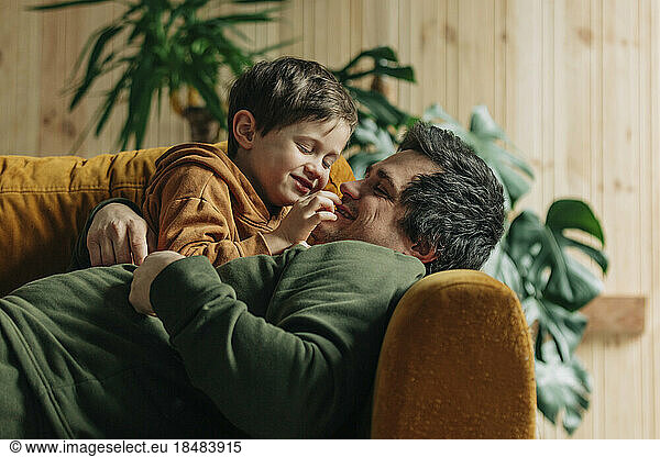 Playful father having fun with son on sofa at home