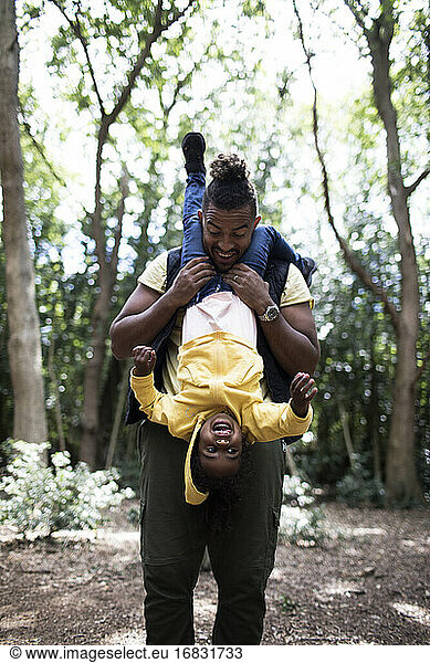 Playful father holding daughter upside down on hike in woods