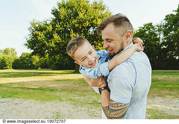 Playful father holding son on field