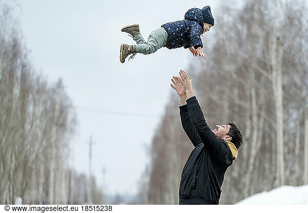 Playful father throwing son in air