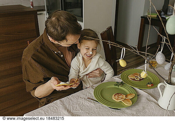 Playful father with daughter enjoying having pancakes for breakfast at home