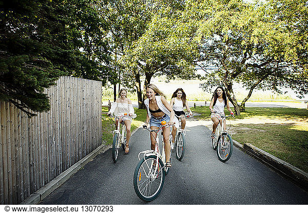Playful friends cycling on road