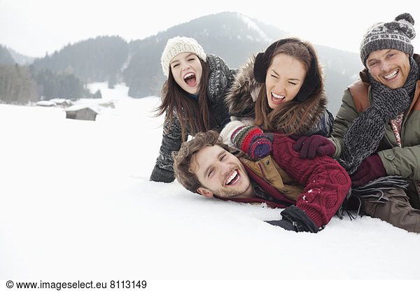 Playful friends laying in snowy field