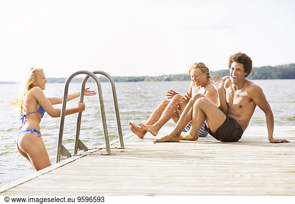 Playful friends on boardwalk at lake