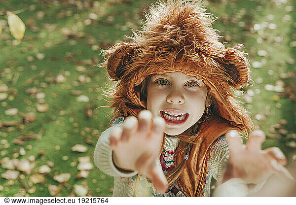 Playful girl with fur hat gesturing in garden
