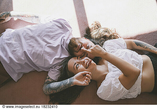 Playful hipster couple lying on bed at home