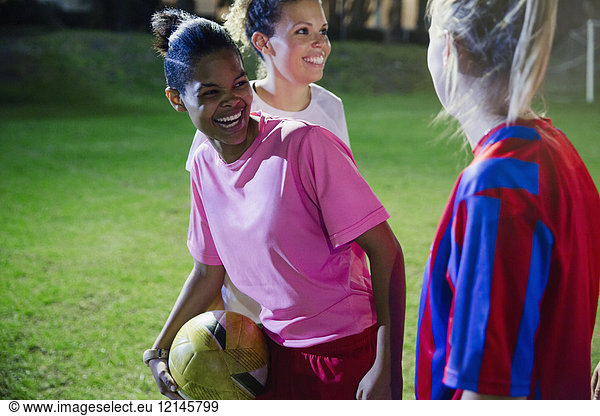 Playful  laughing young female soccer plays on field at night