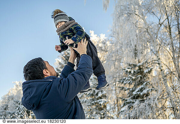 Playful man carrying son in winter park