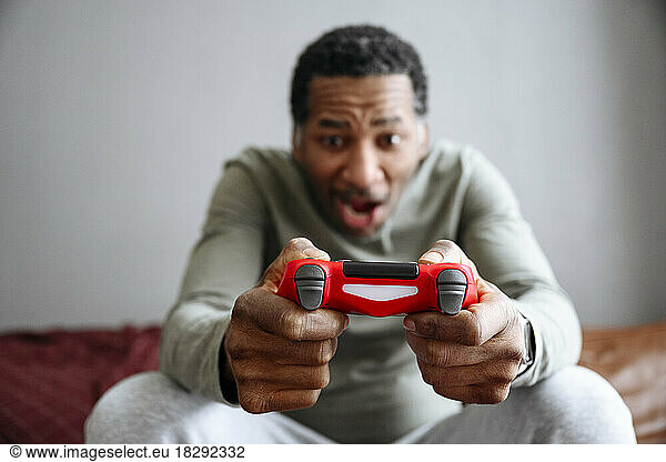 Playful man holding gamepad on sofa