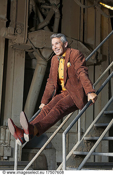 Playful man in full suit balancing on staircase railing