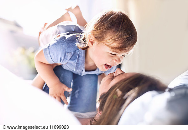 Playful mother holding laughing baby son on knees
