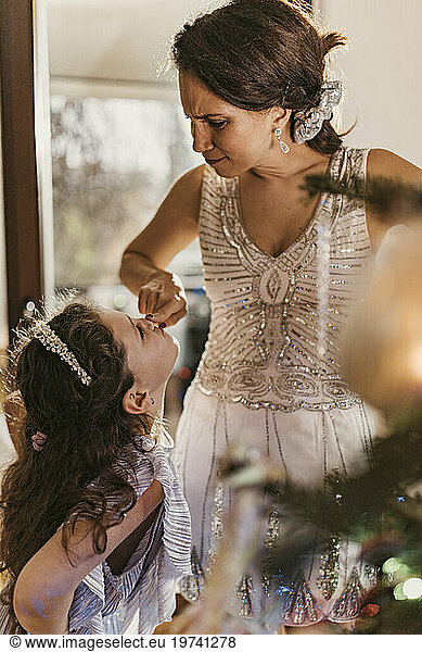 Playful mother touching daughter's nose at home