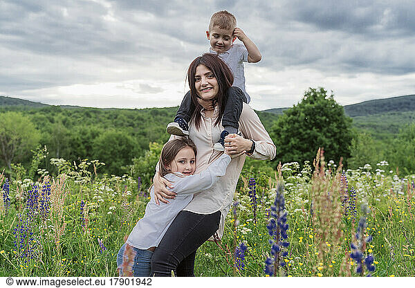 Playful mother with daughter and son in meadow