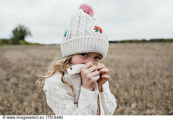 playful portrait of a girl playing in a field hiding and laughing