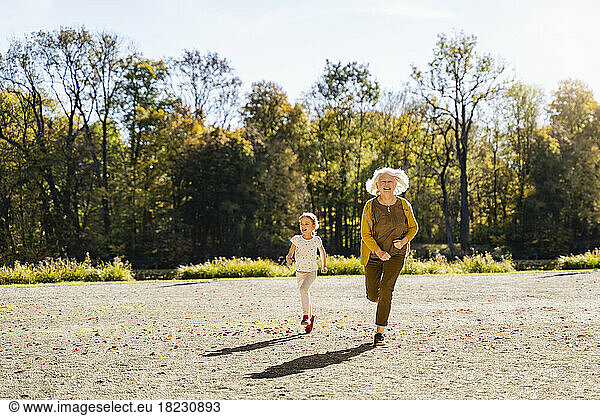 Playful senior woman running with granddaughter in park