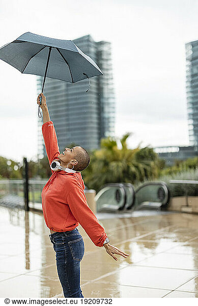 Playful shaved head woman holding umbrella in city