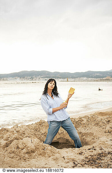 Playful woman digging sand at beach
