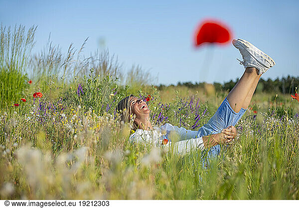 Playful woman having fun amidst flowers in meadow