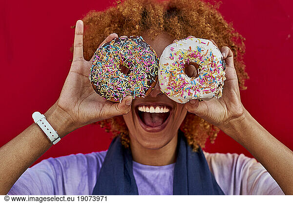 Playful woman holding two donuts in front of her eyes