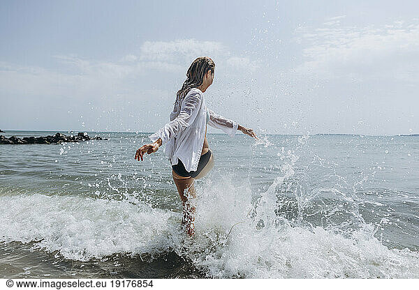 Playful woman splashing water at beach