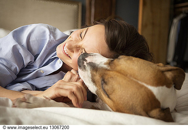 Playful woman with dog on bed at home