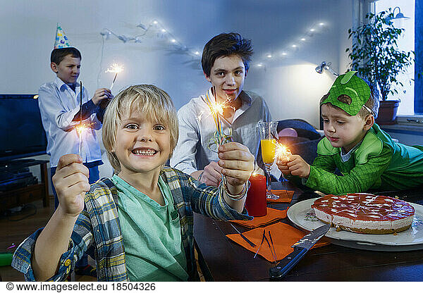 Playful young boys celebrating birthday with sparklers