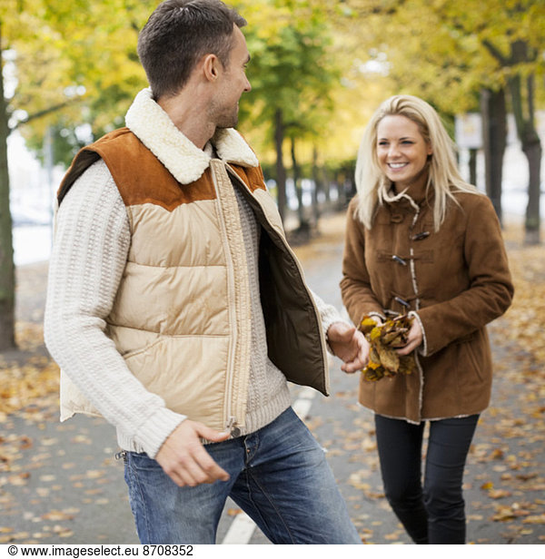 Playful young couple on street during autumn