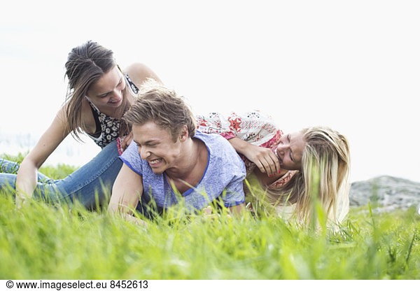 Playful young friends piling on each other at field