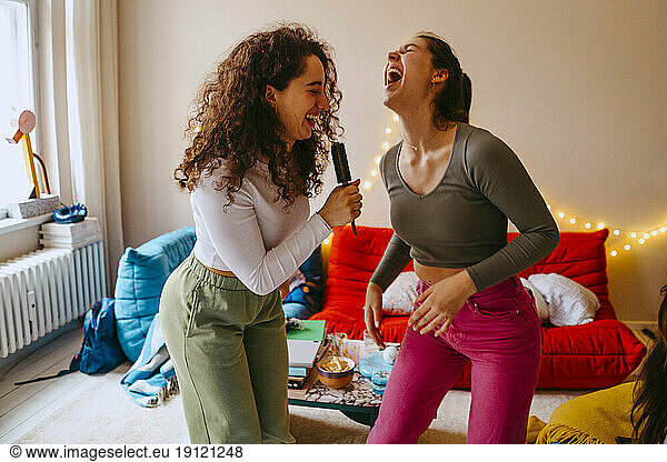 Playful young women enjoying music while singing at home
