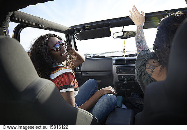 Playful young women enjoying road trip in jeep