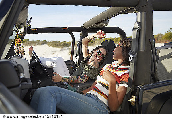 Playful young women friends relaxing  enjoying road trip in jeep