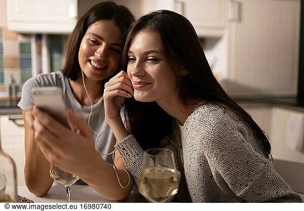 Pleased ladies browsing social media and listening to music