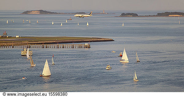 Pleasure boats at Boston Harbor with plane landing at Logan Airport  Boston  Massachusetts  USA