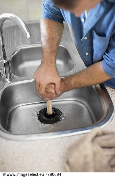Plumber unclogging kitchen sink