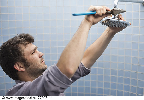 Plumber working on shower head in bathroom