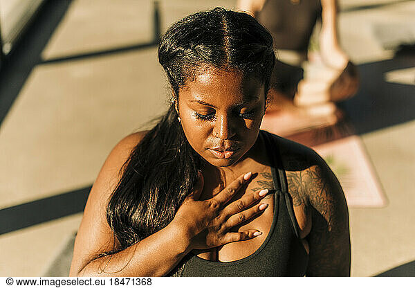 Plus size woman with hand on chest practicing breathing exercise at retreat center