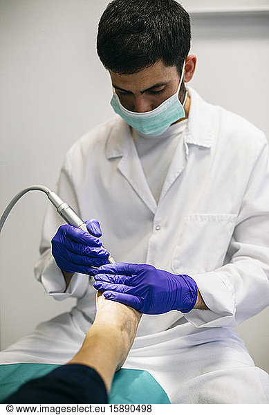 Podiatrist pedicuring woman's foot