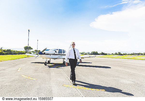 Poilot walking on runway  sports plane in background