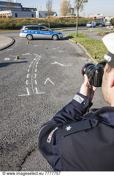 Polizist fotografiert Unfallort eines Verkehrsunfalls