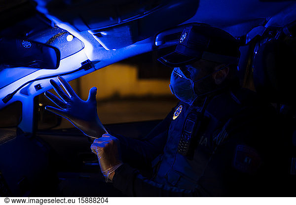 Polizist im Notfalleinsatz  zieht Schutzhandschuhe an