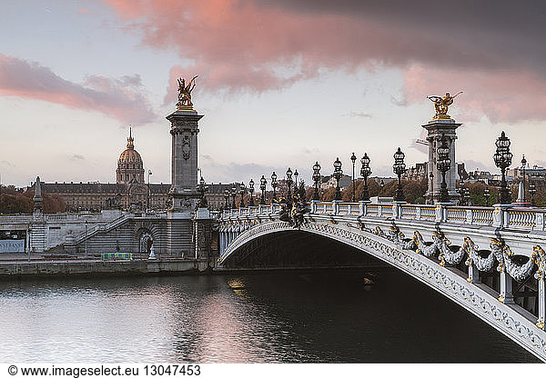 Pont Alexandre III über der Seine vor bewölktem Himmel bei Sonnenuntergang