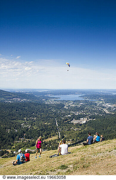 Poo Poo Point is a tourist attraction near Issaquah  WA where hang gliders launch into the clear sky above a thick green forest.