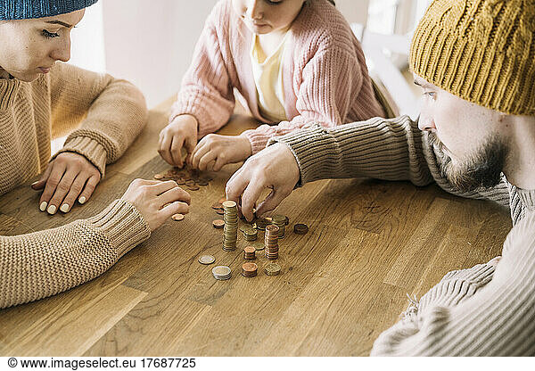 Poor family with winter hats sitting at table counting coins