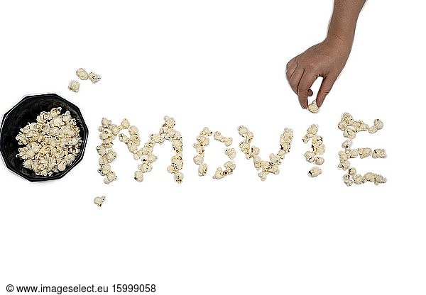 Popcorn isolated on white background forming the word Movie close-up with hand holding popcorn.