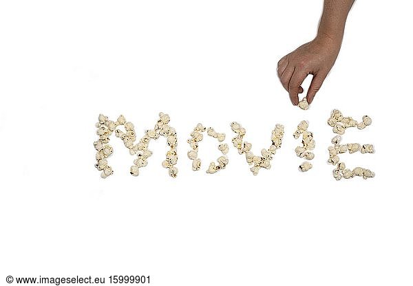 Popcorn isolated on white background forming the word Movie close-up with hand holding popcorn.